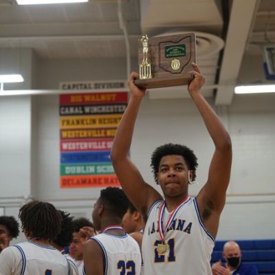 Maceo Williams is showing the trophy by holding it over his head.